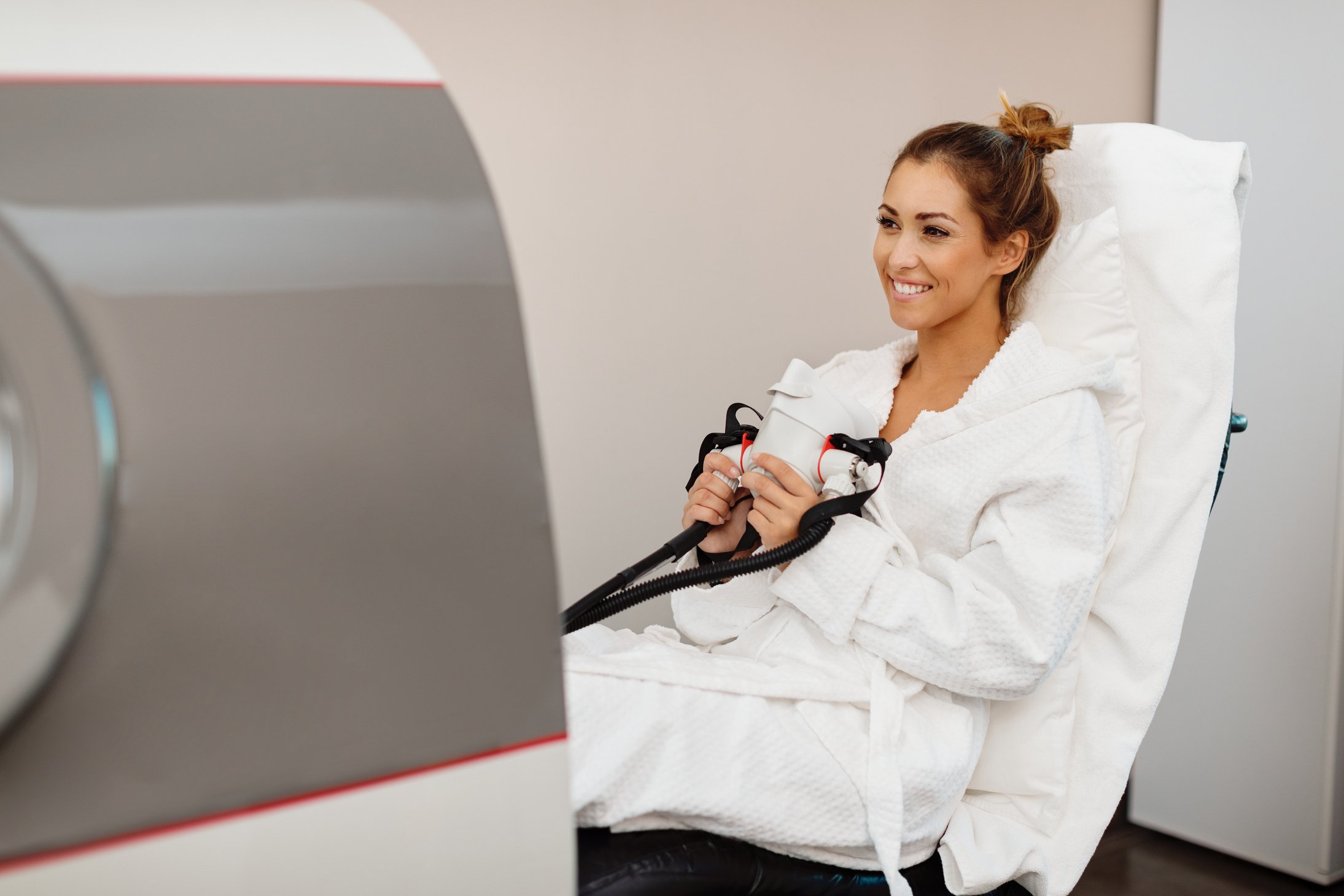 Happy woman receiving oxygen therapy at hyperbaric chamber at health spa.